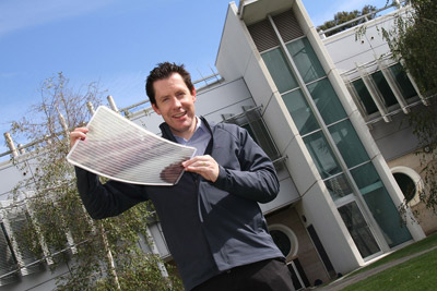 Dr Scott Watkins holding a sheet of flexible solar cells